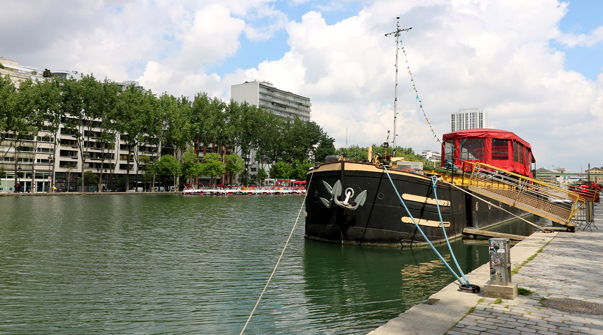 large red and black boat moored on a lake in Paris under a blue sky